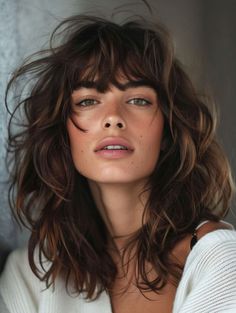 This trendy mid-length haircut with bangs and waves offers a carefree and stylish look. Perfect for a round face, the tousled waves and natural brunette shade create a relaxed, beachy vibe. This hairstyle is ideal for clients wanting a low-maintenance yet fashionable cut that can easily transition from day to night. Layered Haircuts For Medium Hair With Bangs, Shoulder Length Hair Wavy, Wavy Haircuts With Bangs, Curls With Bangs, Bangs 2024, Rich Brunette Hair, Mid Length Curly Hairstyles, Medium Haircuts With Bangs, Wavy Layered Hair