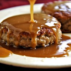 a piece of meatloaf covered in gravy and being drizzled with sauce