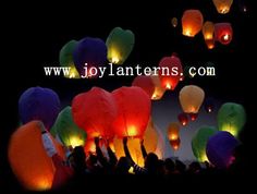 many colorful lanterns floating in the air at night