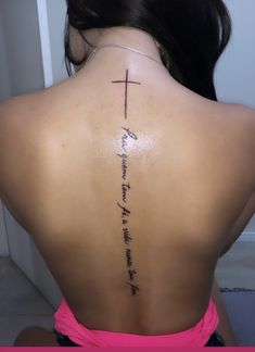 the back of a woman's neck with a cross tattoo on her lower back