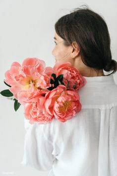 a woman wearing a white shirt holding pink flowers