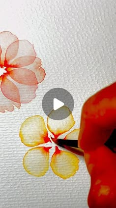 someone is painting flowers with watercolors on the paper and using a pencil to draw them