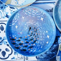 two blue bowls with designs on them sitting next to plates and utensils in the background