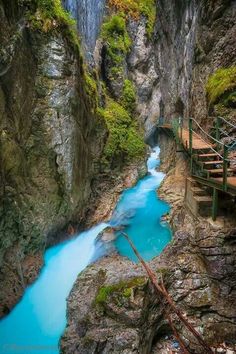 a river flowing through a canyon next to a wooden walkway with steps leading up to it