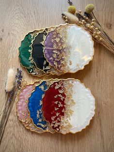 three different colored plates sitting on top of a wooden table next to dried flowers and plants