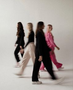 three women walking in the same direction with one woman wearing a pink dress and black blazer