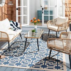 an outdoor living room with wicker furniture and rugs on the floor, along with potted plants