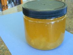 a glass jar filled with yellow liquid sitting on top of a blue piece of paper