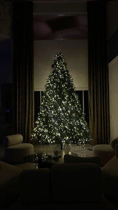 a living room with a lit christmas tree in the corner