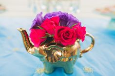 a gold teapot with flowers in it on a blue tableclothed table cloth