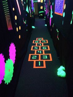 the hallway is decorated with neon lights and black carpeted walls, along with an area rug that looks like a maze