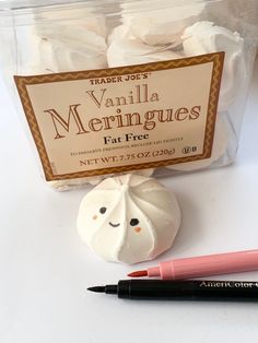 a plastic container filled with white marshmallows next to a marker and pen