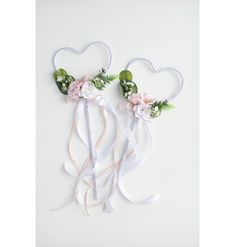 two heart shaped headbands with flowers and ribbons attached to each other on a white background