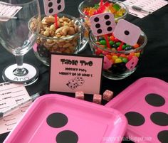 a table topped with pink plates filled with candy and dices on top of it