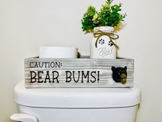 a wooden sign that says caution, bear bums on the side of a toilet