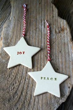 two white ceramic stars with red and white candy canes hanging from them on a piece of wood