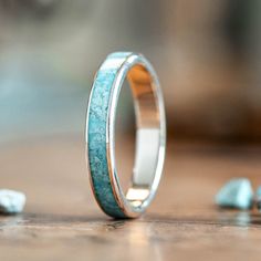 a close up of a wedding ring on a wooden table with blue stones around it