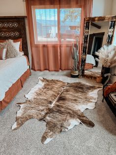 a bed room with a neatly made bed and a cowhide rug