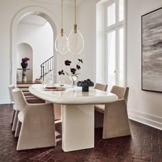 a dining room table with four chairs and a vase on the table in front of it