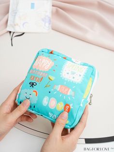 a person is holding a small blue bag with happy birthday designs on it, while another hand holds the case