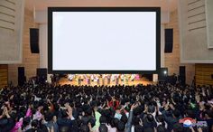 a large group of people sitting in front of a big screen