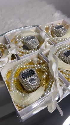 four boxes filled with different types of pearls and jewelry on top of a white table