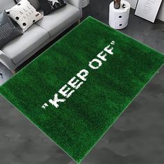 a green rug with the words wet grass written on it in white across from a couch