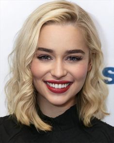 a close up of a person with blonde hair and red lipstick smiling at the camera