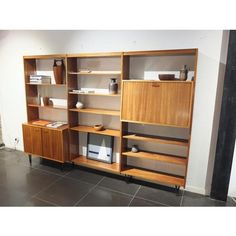 a wooden bookcase sitting on top of a black tile floor next to a white wall