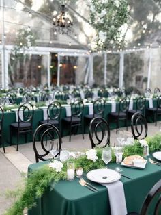 tables set up for an event with green linens and place settings in the center