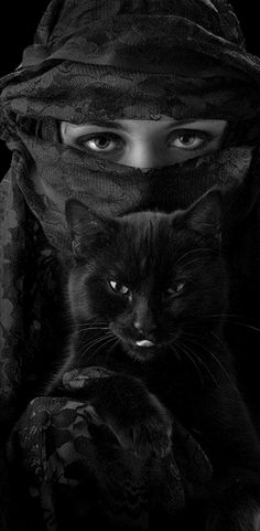 a woman wearing a black veil and holding a cat in her lap with the caption,