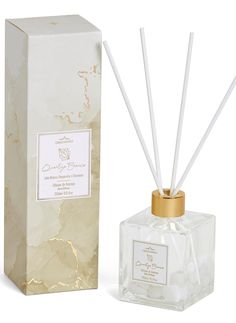 an open box next to a white and gold reed diffuser