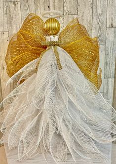 a gold and white angel ornament on top of a wooden box with mesh netting