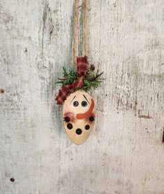 a wooden mask hanging from a rope on a white wall with red and green decorations