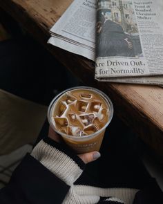 a person holding up a cup of iced coffee