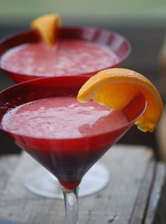 two glasses filled with liquid and garnished with an orange slice