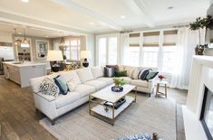 a living room filled with furniture next to a kitchen and breakfast nook area on top of a hard wood floor