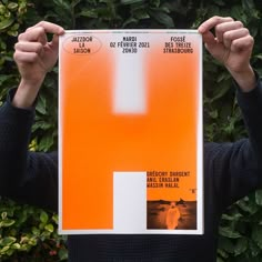 a man holding up an orange poster in front of his face