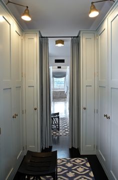 an empty hallway with white closets and blue rug on the floor in front of it