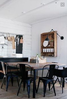 a dining room table and chairs in front of a white brick wall with hanging utensils