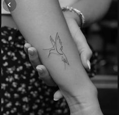 two hands holding each other with a small tattoo on the wrist and one has a bird on it