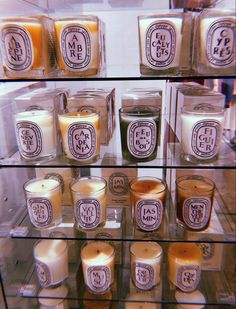 many candles are on display in a glass case with the words m & s written on them