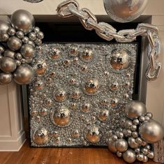 a bunch of silver balls and chains are on the floor in front of a fireplace