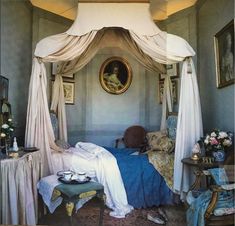 an old fashioned bedroom with blue walls and white drapes on the canopy over the bed