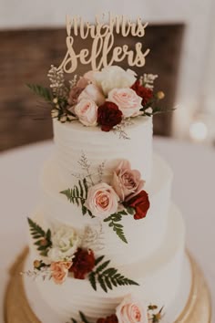 a white wedding cake with flowers and the words mr and mrs spelled on top is sitting on a gold plate