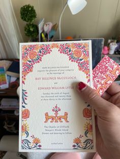 a person holding up a wedding card in their hand