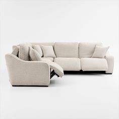 a white couch with pillows on it sitting in front of a white wall next to a chair