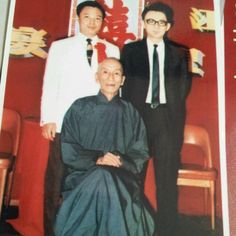 an old photo of two men standing next to each other in front of a red wall