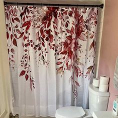 a white toilet sitting next to a bathroom sink under a window covered in red leaves