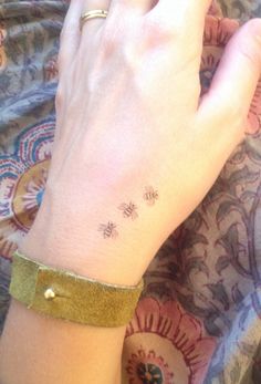 a woman's hand with a small bee tattoo on her left wrist and gold band